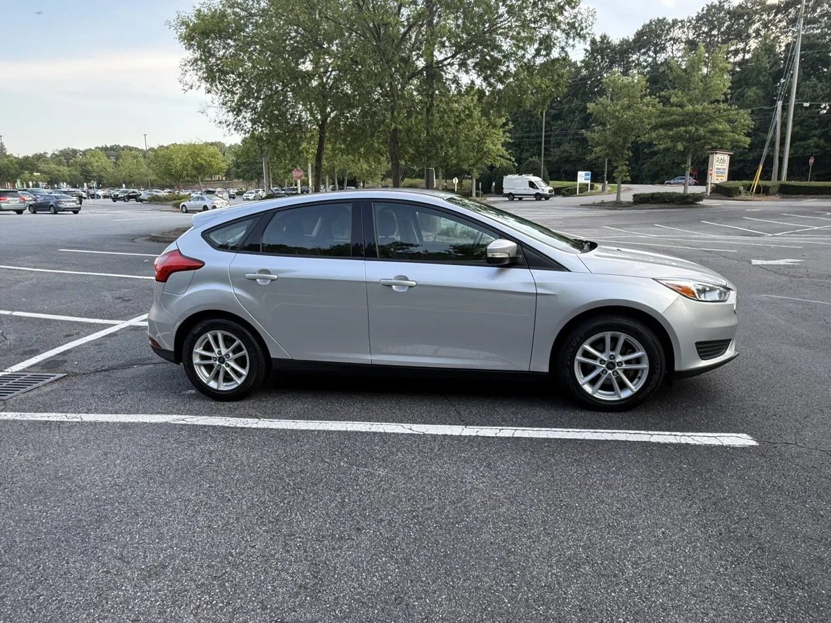 Silver Ford Focus hatchback parked in empty parking lot with trees in background